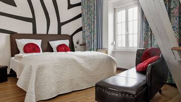 A bedroom with a bed, a chair, a window, and a curtain.