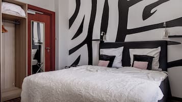 Een slaapkamer met een bed, een kledingkast, een spiegel en een muur met een zwart-wit abstract ontwerp.