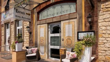 Entrada de un hotel con un letrero que dice 'Hôtel-Restaurant' y un letrero para 'Entrée' que indica un hotel y restaurante.
