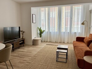 Un salon avec une télévision, un canapé, une table basse et une plante.