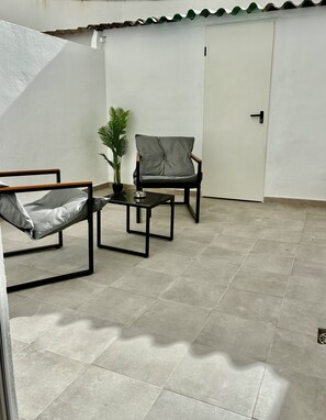A patio with a chair, a table, and a potted plant. - Modern apartment with a terrace in Malvarrosa, Valencia Beach (València)