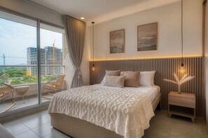 A modern bedroom with a large bed, a view of a construction site, and a balcony with wicker chairs. - MARESIA SANTA MARTA (Santa Marta)