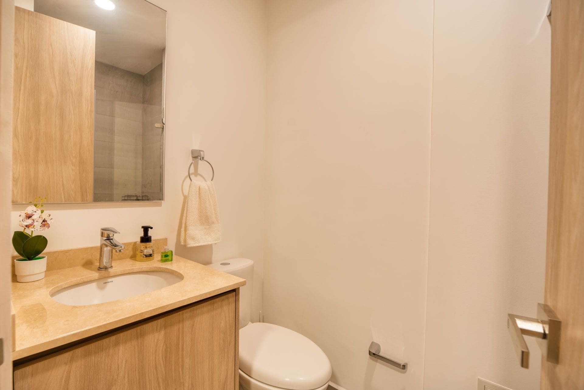 Ein Badezimmer mit einem Holzbidet, einer weißen Toilette, einem Spiegel und einem Handtuch an einem Metallring.