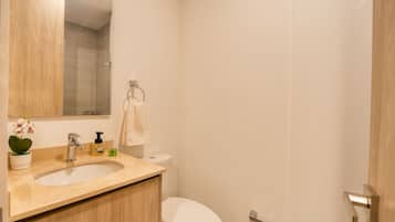 Ein Badezimmer mit einem Holzbidet, einer weißen Toilette, einem Spiegel und einem Handtuch an einem Metallring.