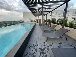 A rooftop pool with lounge chairs, a pergola, and a city view. - The Lennox Apartments-Airport (Accra)