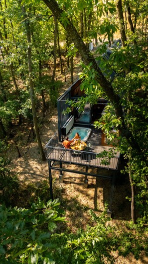 A hot tub on a wooden deck surrounded by trees.