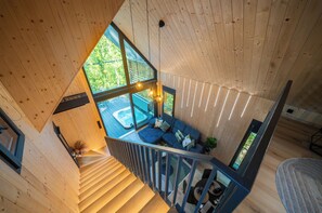 A wooden interior with a staircase leading to a balcony with a hot tub.