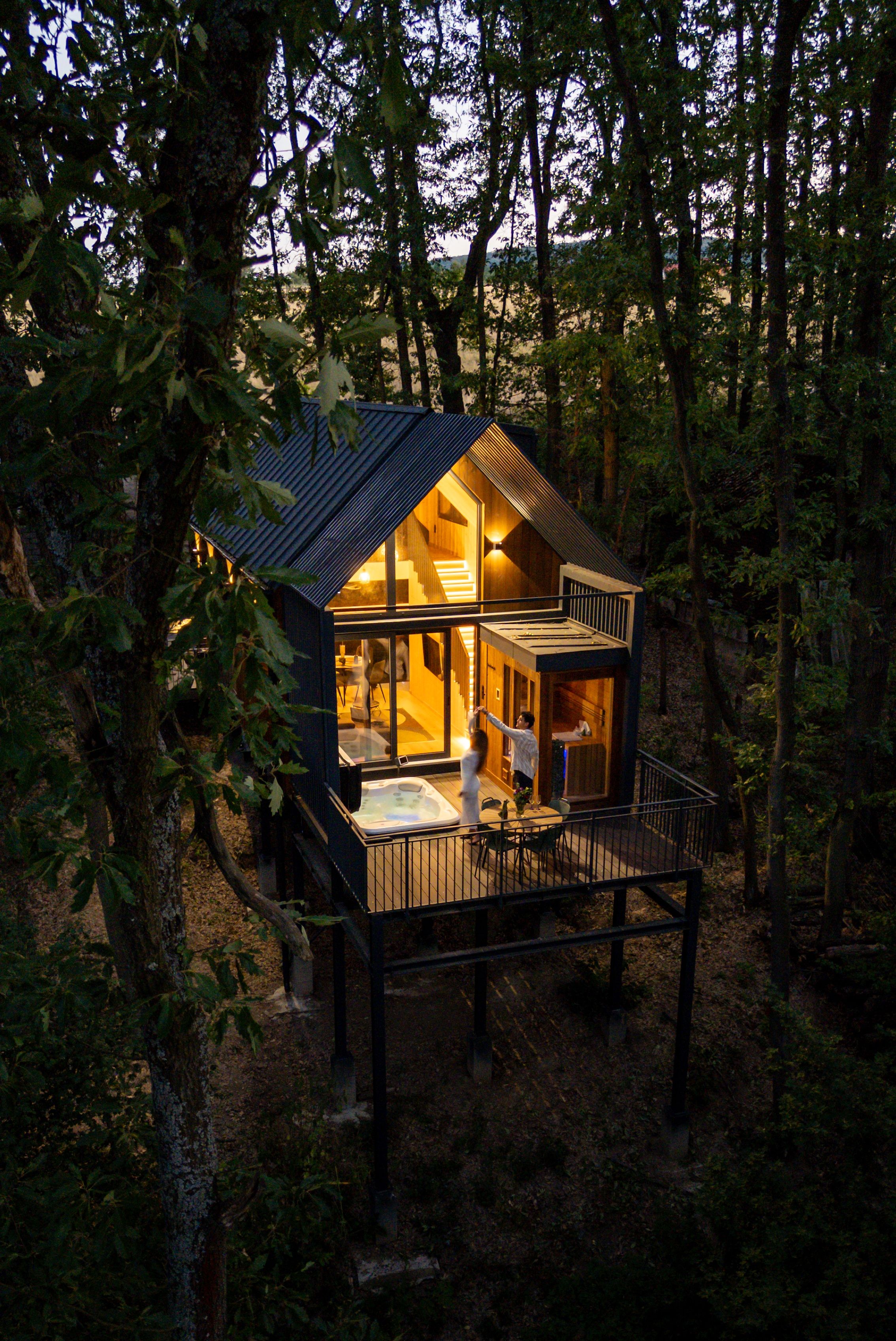 A cabin with a deck, a hot tub, and a staircase leading to the upper level.