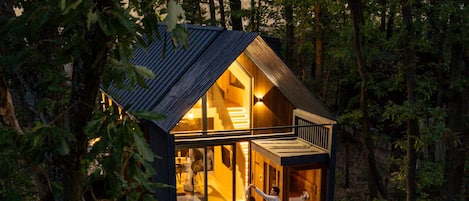 A cabin with a deck, a hot tub, and a staircase leading to the upper level.
