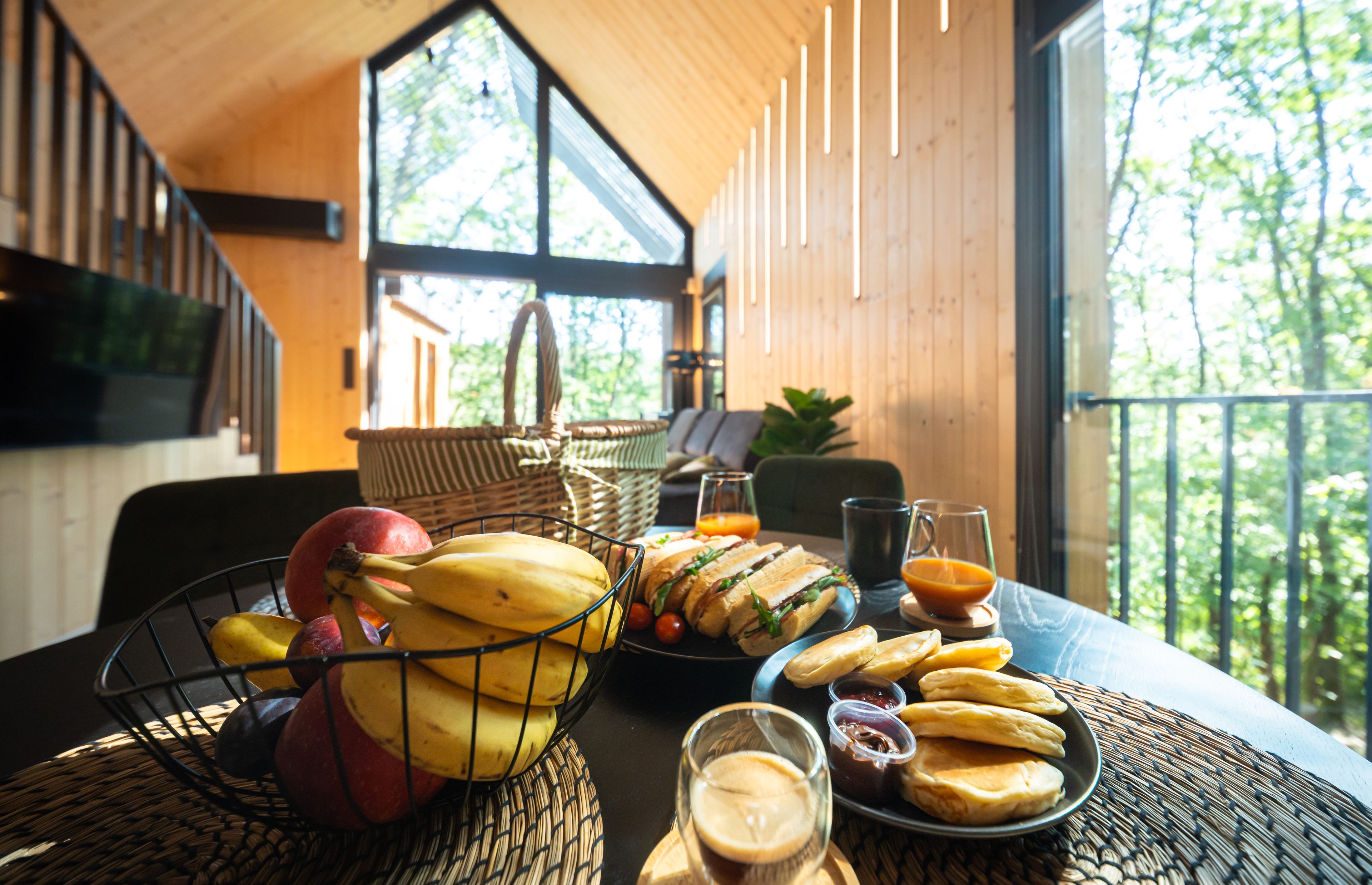 Een ontbijttafel met fruit, belegde broodjes en drankjes.
