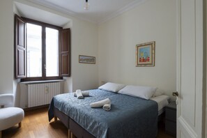 A bedroom with a bed, a chair, a radiator, and a window. - Porta Pia Enchanting Apartment (Roma)