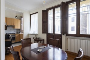 A dining area with a round table, chairs, and a view of the kitchen. - Porta Pia Enchanting Apartment (Roma)