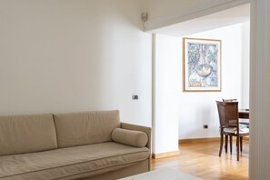 A living room with a beige sofa, a dining table with chairs, and a framed artwork on the wall. - Porta Pia Enchanting Apartment (Roma)
