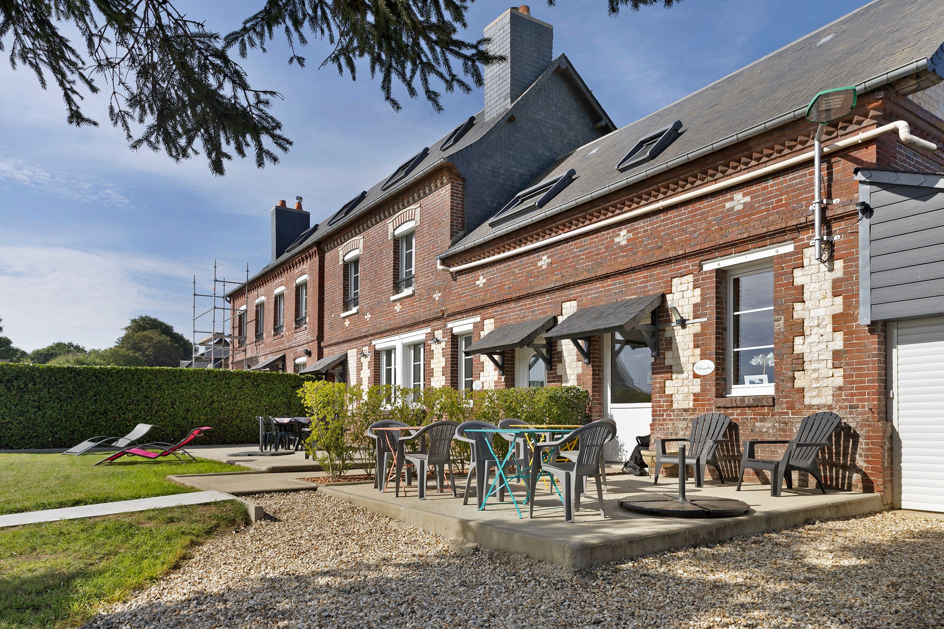 A two-story brick building with a patio area featuring outdoor seating and a small garden.