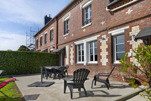 A two-story brick house with a patio area featuring outdoor furniture. - Guest room 'L'ancienne Forge - Le Marteau' with shared terrace, Wi-Fi and air conditioning (Louvetot)