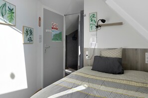 A bedroom with a bed, a bedside table, a lamp, and a door with a sign. - Guest room 'L'ancienne Forge - Le Marteau' with shared terrace, Wi-Fi and air conditioning (Louvetot)