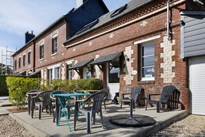 A brick building with a patio area featuring outdoor seating and tables. - Guest room 'L'ancienne Forge - Le Marteau' with shared terrace, Wi-Fi and air conditioning (Louvetot)