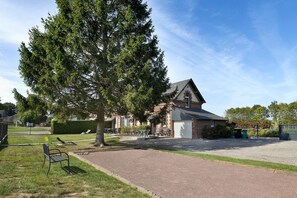 A building with a brick facade, a gravel driveway, and outdoor seating. - Cottage 'L'ancienne Forge' with Private Terrace, Private Garden and Wi-Fi (Louvetot)