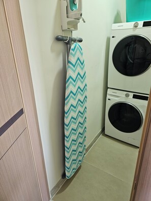 Ein Waschbereich mit Wandbügeleisen, Waschmaschine und Trockner.