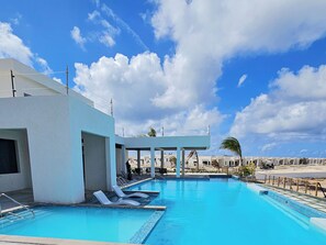 Ein Pool mit Liegestühlen, einem überdachten Bereich und blauem Himmel.