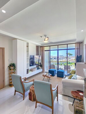 Ein modernes Wohnzimmer mit Flachbildfernseher, Sitzecke und Blick auf die Stadt.