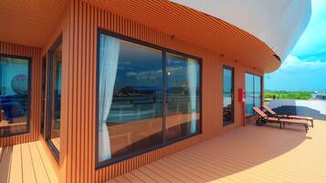 A modern building with large windows and a deck area with lounge chairs.