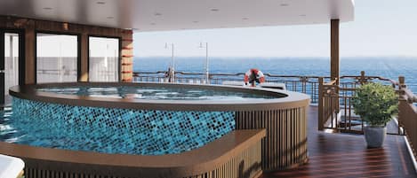 A hot tub with a view of the ocean, wooden deck, and a lifebuoy.