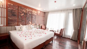 Ein Hotelzimmer mit einem großen Bett, Holzboden, einer Wandverkleidung und Blick ins Freie.
