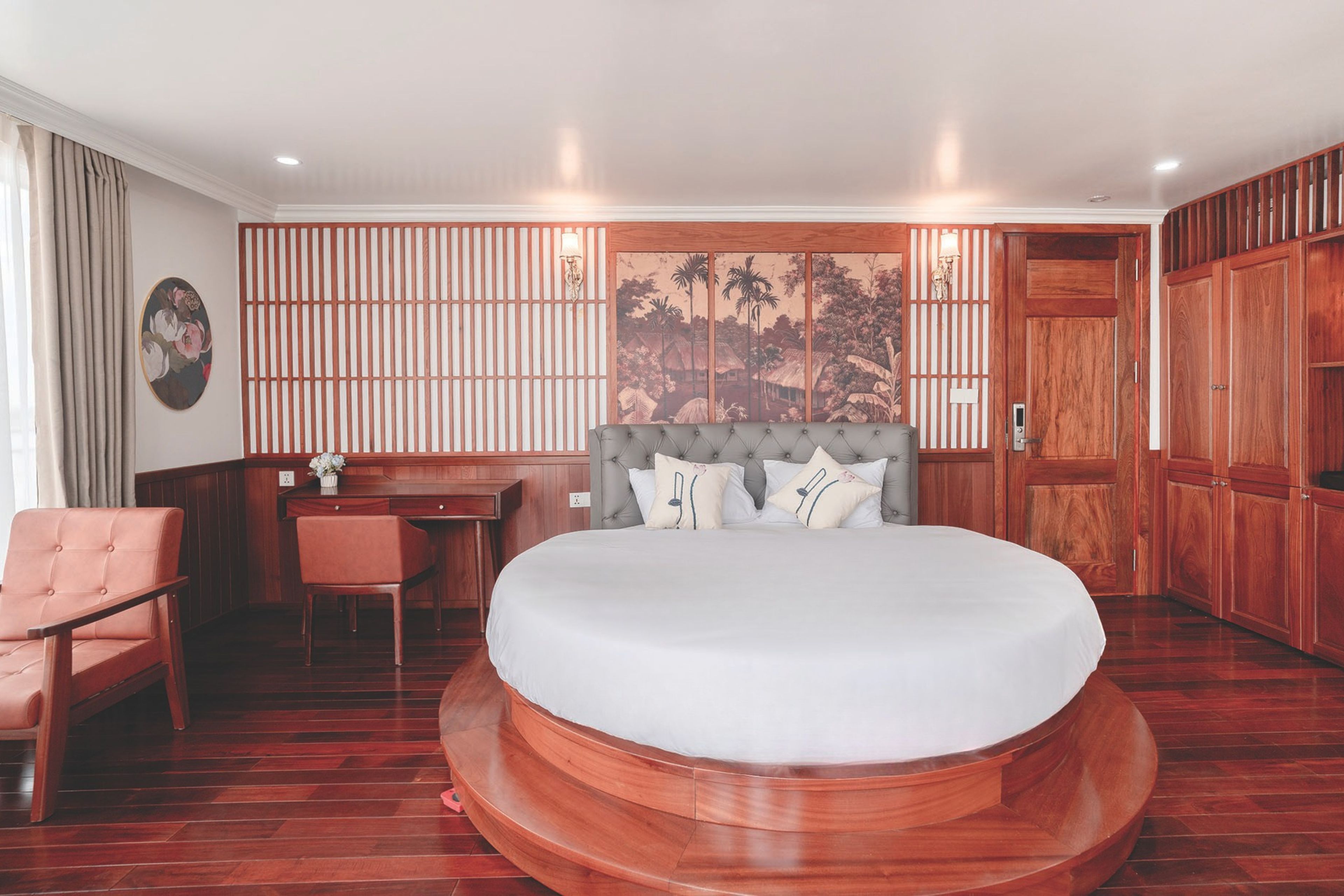 A bedroom with a large bed, a desk, a chair, and a wardrobe.