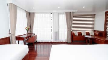Habitación de hotel con dos camas, un escritorio, un sofá y una ventana con persianas.
