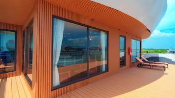 Un edificio moderno con grandes ventanales y una terraza con sillones de descanso.
