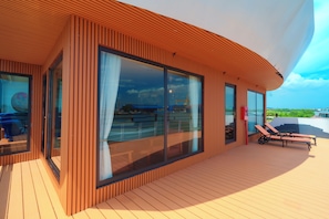 A modern building with large windows and a deck area with lounge chairs. - Daiichi Luxury Cruise (Hai Phong)