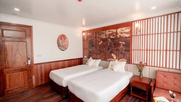 A hotel room with two beds, a wooden door, a wall-mounted artwork, and a traditional-style partition.