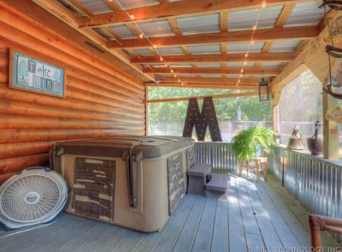 Una terraza de madera con un jacuzzi, un ventilador y un letrero.