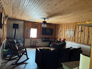 A wooden-paneled room with a ceiling fan, a television, and a rocking chair.
