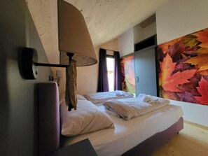 A hotel room with two beds, a wooden ceiling, a wall with autumn leaves, and a window with curtains. - One-bedroom Cabin (Sankt Georgen am Kreischberg)