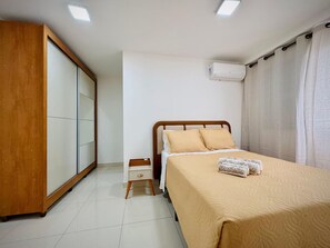 A bedroom with a bed, a wardrobe, a bedside table, and an air conditioning unit. - 2-bedroom apartment near 44th Street | Swimming pool | Garage | Air conditioning (Goiânia)