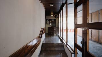 A corridor with wooden paneling, a staircase, and a door leading outside.