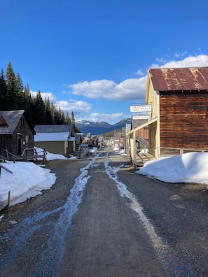 A street with buildings, a wooden structure, and snow on the ground. - Room 3 - St. George Hotel (Barkerville)