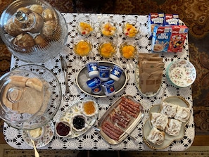 A table with various food items, including pastries, fruits, and packaged goods. - Room 3 - St. George Hotel (Barkerville)