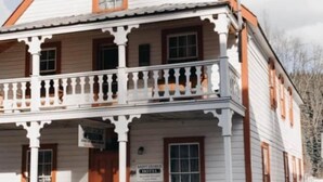 Um edifício de dois andares com varanda, uma placa indicando 'Saint George Hotel' e um aviso com a palavra 'Quartos'.