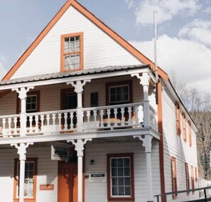 A two-story building with a balcony, a sign indicating 'Saint George Hotel,' and a 'Rooms' sign. - Room 2 - St. George Hotel (Barkerville)