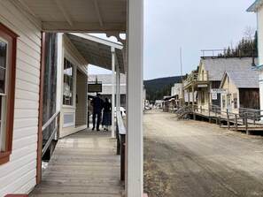 A wooden building with a porch, a sign for a tooth extraction service, and a road leading to other buildings. - Room 2 - St. George Hotel (Barkerville)