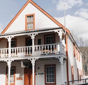Un bâtiment à deux étages doté d’un balcon, d’une enseigne indiquant « Hôtel Saint-Georges » et d’une autre enseigne indiquant « Chambres ».
