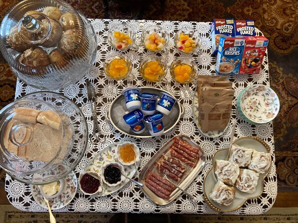 A table with various food items and condiments, including pastries, fruit, yogurt, and packaged snacks.