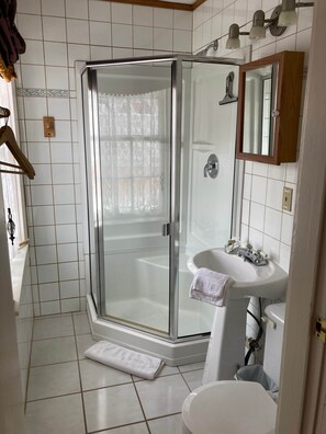 A bathroom with a glass-enclosed shower, a white sink, and a mirror above it.
