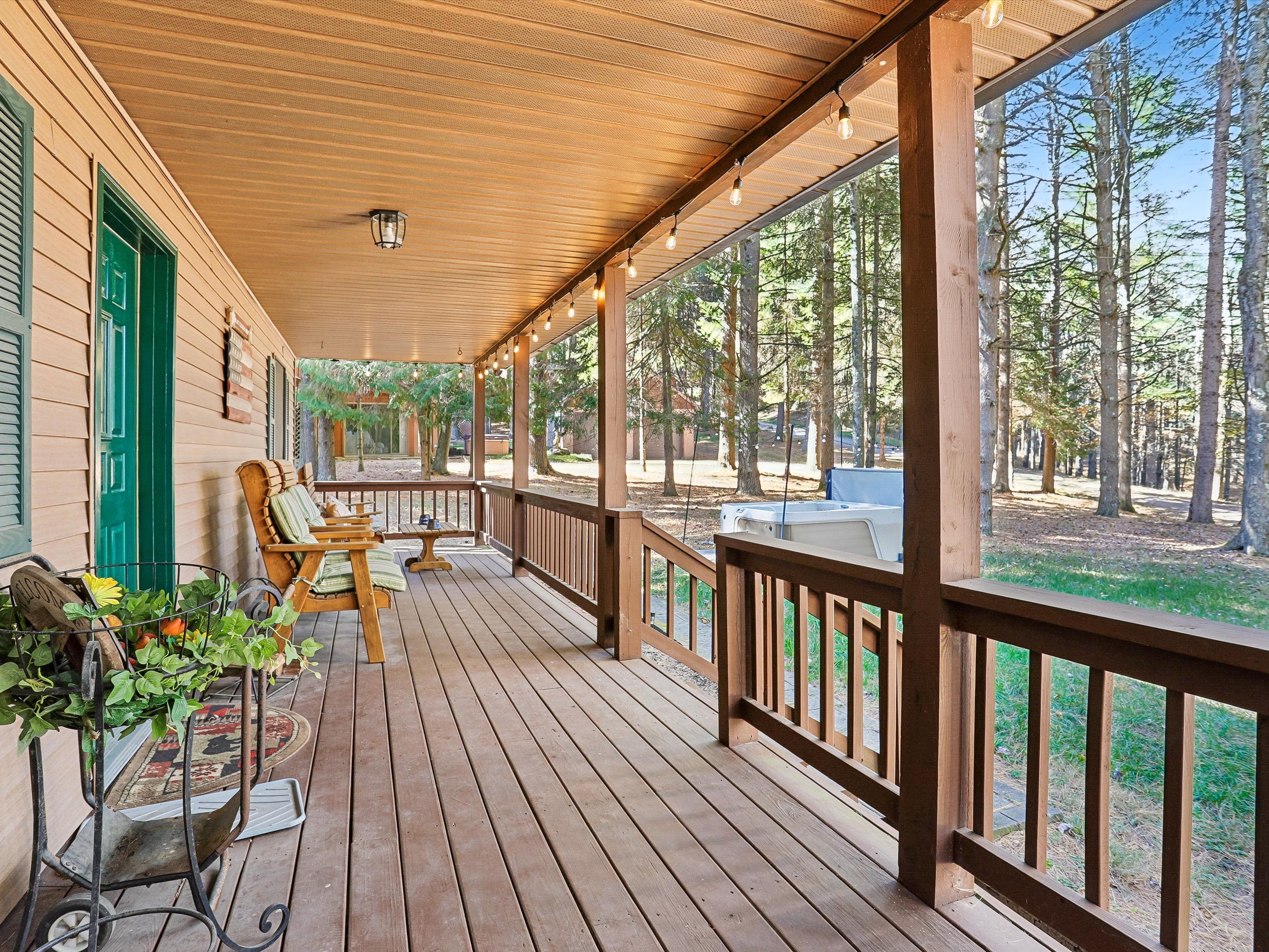 A wooden deck with outdoor seating and a view of a forest.