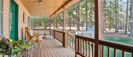 A wooden deck with outdoor seating and a view of a forest.