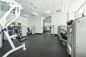Ein Fitnessstudio mit verschiedenen Trainingsgeräten, einem schwarzen Boden und weißen Wänden.