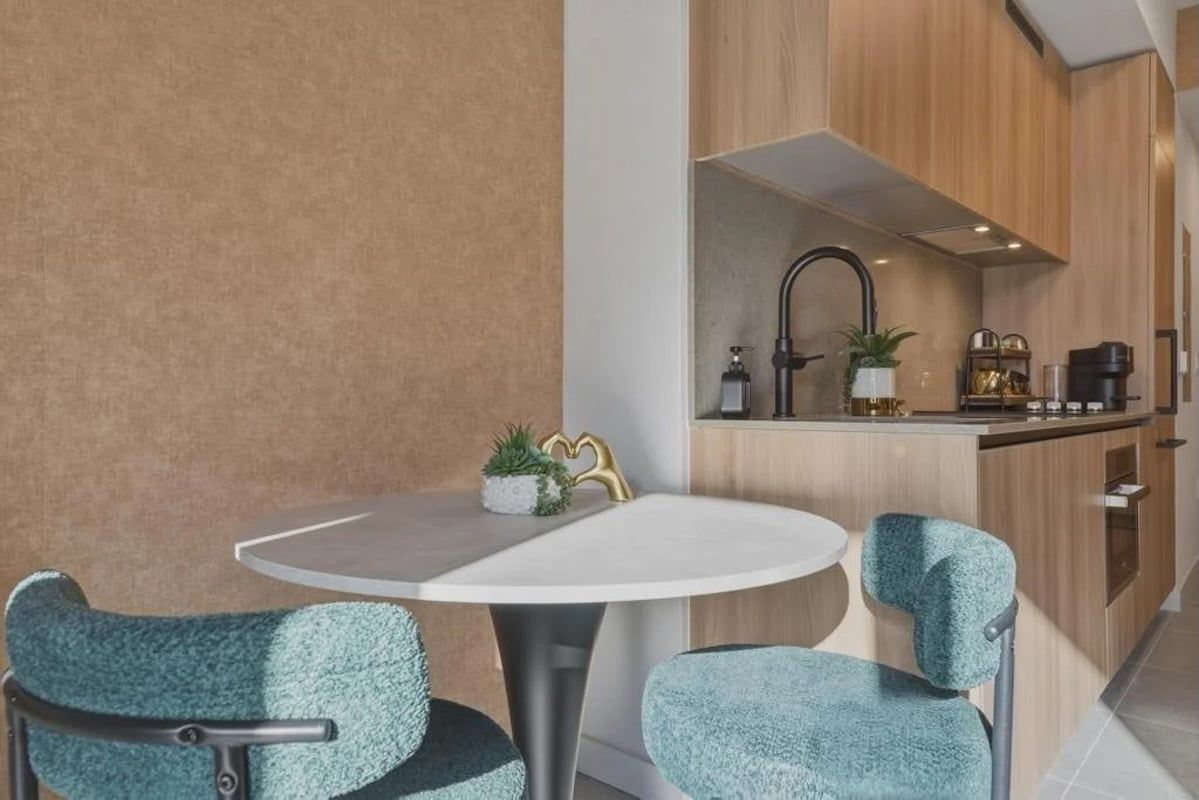 Una cocina moderna con una mesa redonda y dos sillas, un lavabo y una cafetera.